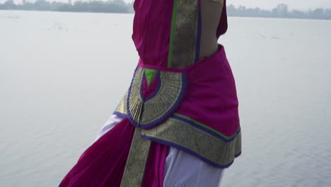 una bailarina de bharatnatyam que muestra una pose clásica de bharatnatyam en la naturaleza del lago vadatalav, pavagadh