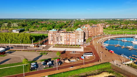 beautiful buildings at the waterfront of lelystad, the netherlands. sunny view of the green city on sunny day from drone footage.
