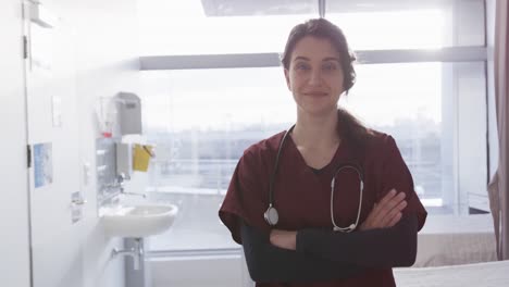 Portrait-of-happy-caucasian-female-doctor-in-hospital-corridor,-slow-motion