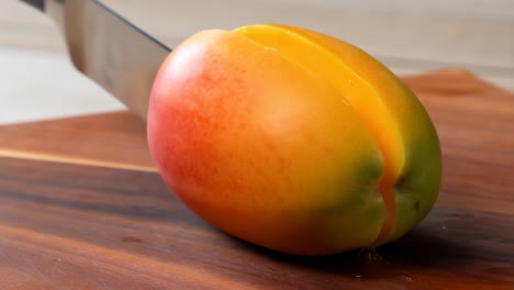 slicing a ripe mango on a wooden cutting board