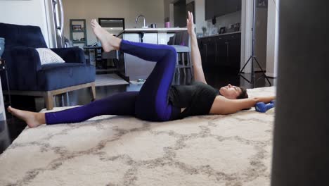Young female working out in living room on white rug, near kitchen, sliding reveal view