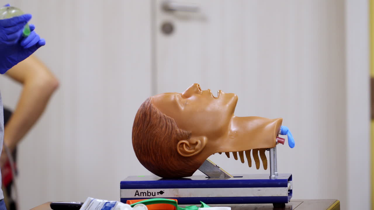 Testa di manichino usata per l'addestramento alla tecnica di intubazione. Messa a fuoco selettiva sull'attrezzatura usata dai tirocinanti nelle mani del medico.