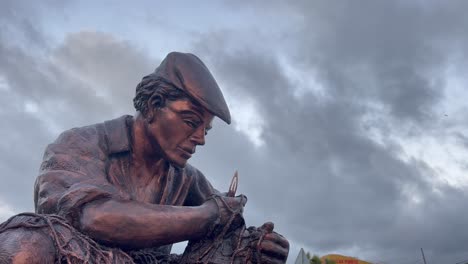 Close-up-shot-of-sailor-statue-in-the-port-of-Spain,-reflect-the-hardships-and-challenges-of-a-life-spent-at-sea,-while-the-intricacy-of-the-net-he's-working-on-showcases-the-skill-and-expertise