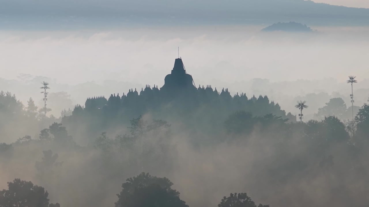 Il Tempio di Borobudur che emerge dalla nebbia mattutina, atmosfera serena e paesaggio naturale mozzafiato in Indonesia.