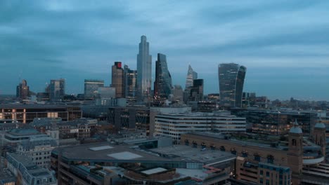 Rotierende-Parallaxen-Drohnenaufnahme-Von-Zentralen-Londoner-Wolkenkratzern-Zur-Blauen-Stunde-Des-Sonnenuntergangs