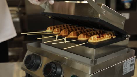 cocinar palitos de waffle en una máquina comercial de waffles