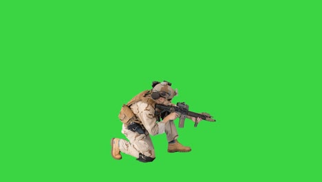 soldier sits down for aiming and shooting with rifle on a green screen, chroma key