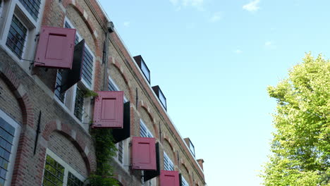 Edificio-De-Ladrillo-Con-Contraventanas-Rojas-En-El-Antiguo-Orfanato-De-Relais-Y-Châteaux-Weeshuis-Gouda,-Países-Bajos