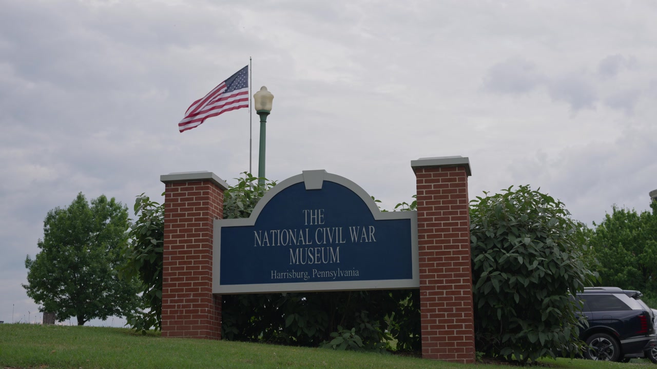 Veduta cinematografica dell'insegna del Museo Nazionale della Guerra Civile e della bandiera americana a Harrisburg, Pennsylvania, che evidenzia il turismo del patrimonio storico militare e un notevole punto di riferimento culturale.