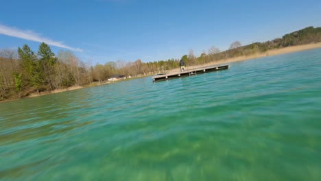 young-dj-playing-music-dancing-and-performing-on-a-pier-in-a-lake-in-austria-on-a-sunny-spring-day