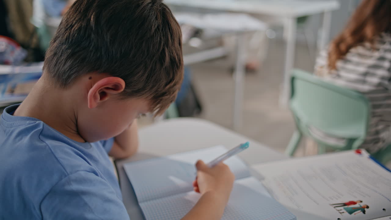 Preteen schoolboy studying classroom sitting desk closeup. Kid writing exercise