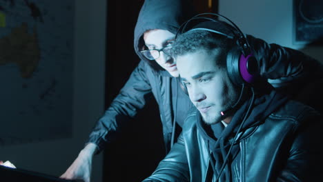 two young guys talking and discussing while hacking in dark room late at night