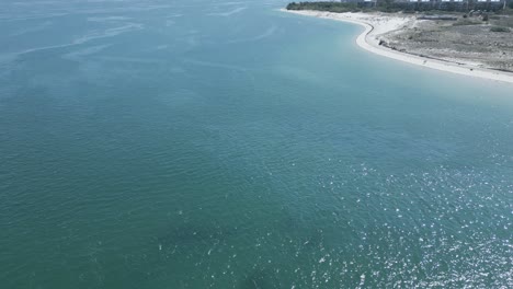 Aerial-panning-shot-showing-turquoise-ocean-and-Troia-Island-during-sunny-day-in-Portugal