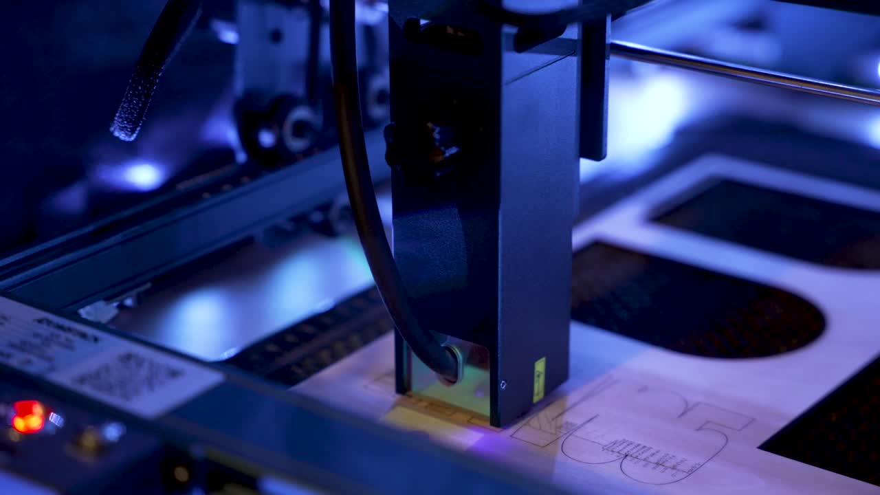 Laser engraver head cutting a pattern into a wooden sheet