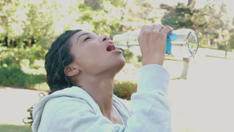 Fit-brunette-drinking-water-after-her-jog-in-the-park