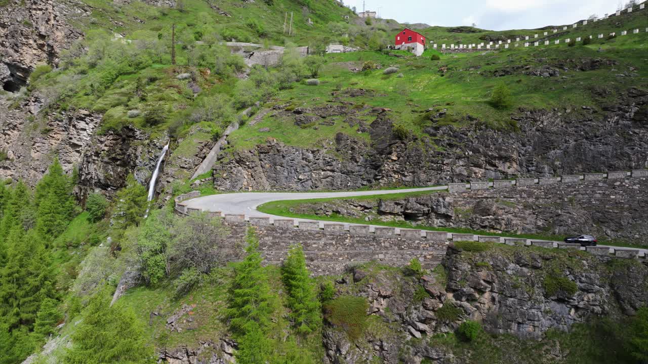 vista aérea carretera de montaña vientos a través de un terreno verde exuberante, ofreciendo una impresionante vista del paisaje natural con un coche que conduce a lo largo de la ruta panorámica