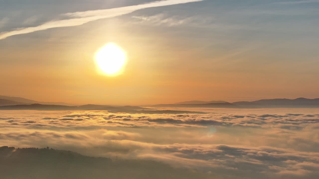 Wunderschöner Sonnenuntergang von einem Berg aus, Wolken und Nebel bedecken das tiefer gelegene Land
