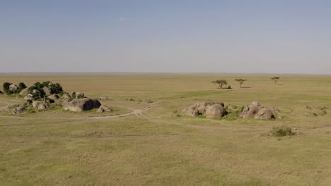 stone islands and a safari tour car parked in the shadow of the tree in serengeti national park, tanzania