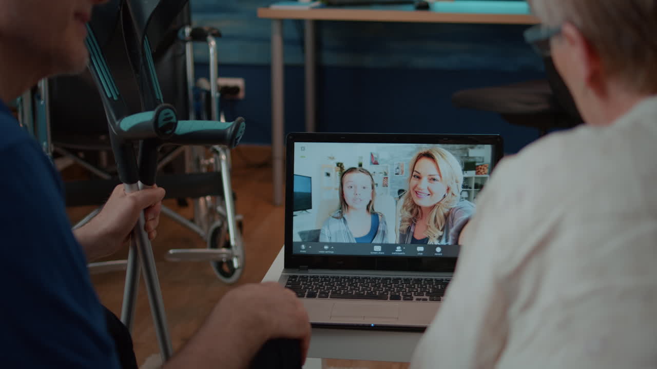 Family video call on laptop with crutches and wheelchair in the background