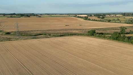 Establecimiento-De-Tomas-De-Drones-De-Campos-De-Cultivo-De-Trigo-Con-Pilones-Y-Cosechadora-Y-Tractor-Con-Remolque-La-Distancia-A-La-Hora-Dorada-Del-Reino-Unido