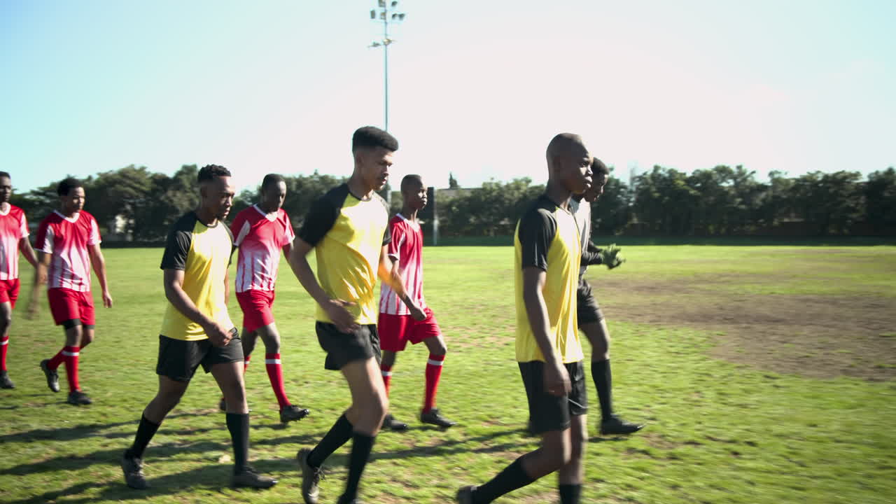 Walking on soccer field, male soccer players in uniforms preparing for match