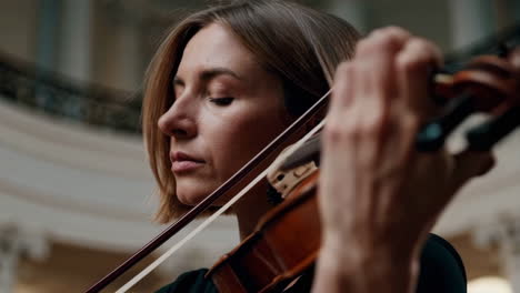 woman playing violin in a grand hall