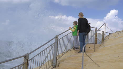 mom and child looking at sea when high splashes appearing in front of them