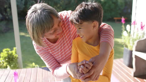 Happy-senior-biracial-grandmother-and-grandson-doing-yoga,-smiling-on-terrace,-slow-motion