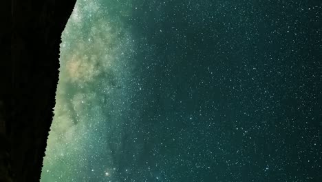 the milky way core ascending above the landscape in silhouette - vertical time lapse