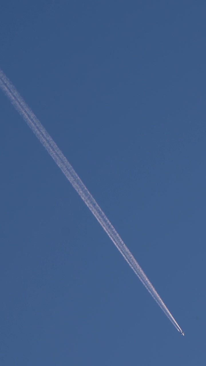 Pesawat jet meninggalkan jejak kondensasi melesat melintasi langit biru cerah dalam penerbangan di ketinggian tinggi