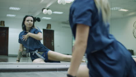 Caucasian-female-dancer-choreographer-performing-contemporary-dance-routine-on-the-floor-against-the-mirror-wall-in-a-dance-studio