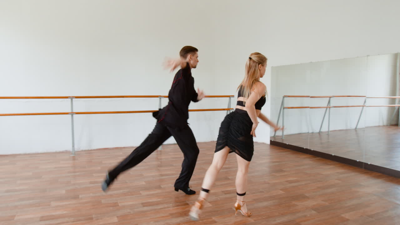 A male and female couple practicing ballroom dance in a bright studio