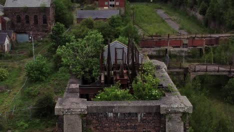 abandoned overgrown landmark rusting coal mine industrial museum buildings aerial view orbit right