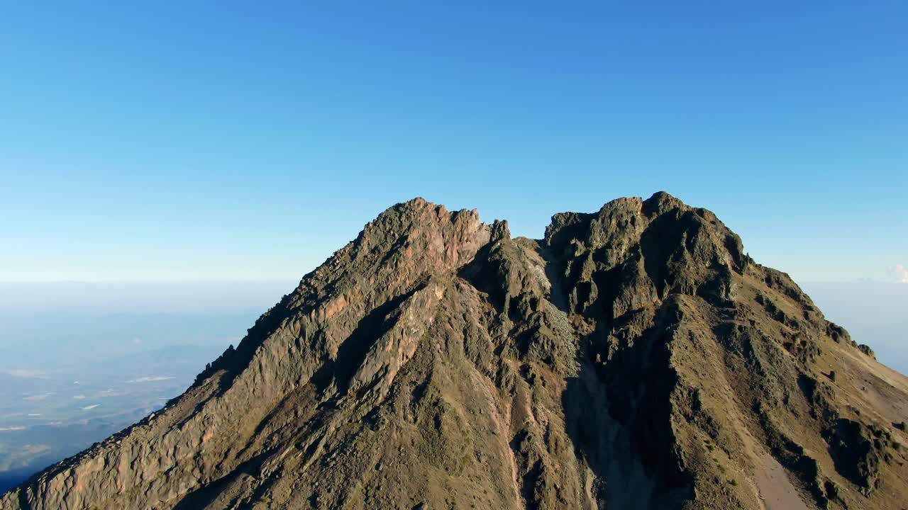Slow motion dolly in aerial overlooking the rocky peak of the Nevado de Colima volcano