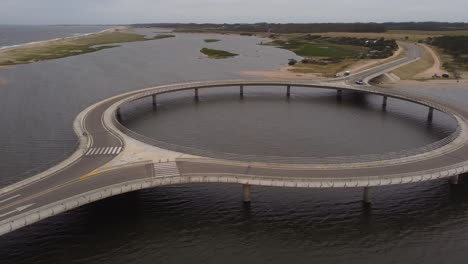 isolated car driving on circular bridge at laguna garzon, uruguay