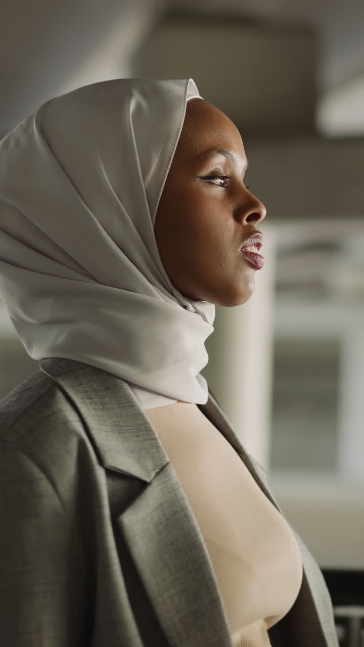 Young black muslimah walks looking around along waterfront under bridge close side view. Arabian woman visits old city. Islamic traditions and modernity
