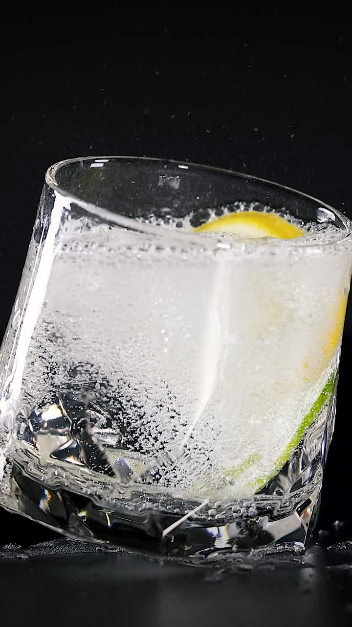 el vaso gira con rodajas de limón y cubitos de hielo.