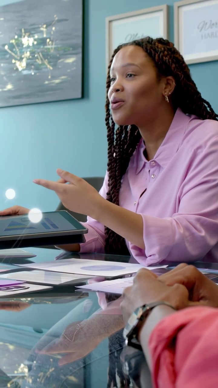 Vertical video: Woman leading tech meeting pointing at tablet causing overlay to pulse showing UI