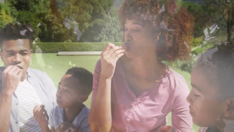 Animation-of-happy-african-american-family-eating-outdoors-over-leaves
