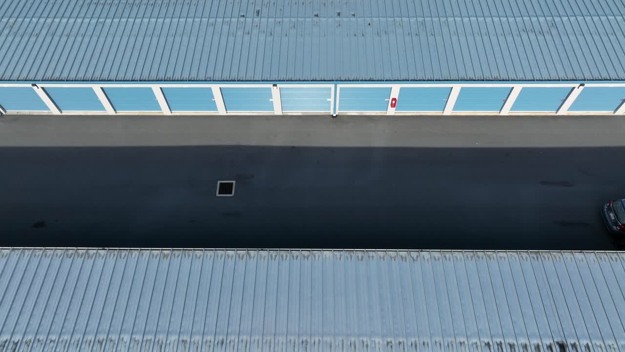 Drone flight over warehouse temporary storage garages in blue color at sunny day. Industrial buildings in suburbia in USA. Top down
