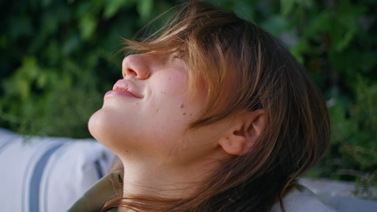 Serene woman leaning back with eyes closed enjoying moment of relaxation closeup