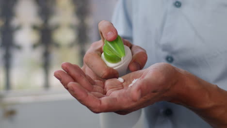 young man squeezing a white moisturizer from a tube on his hand close-up. morning routine. beauty and care concept.