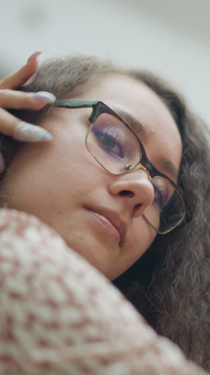 primer plano de una mujer sonriente ajustando su cabello mientras mira con confianza a la cámara con ojos suaves y expresivos, el fondo borroso con la gente agrega profundidad y una animada atmósfera de centro comercial