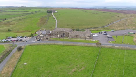 sideways and pan drone footage of a yorkshire country pub including farmland, fields and moorland, country roads with car movement, dry stone walls, telegraph poles