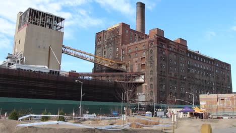 bikers ride in park, domino sugar factory in brooklyn