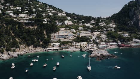 drone shot pulling away from capri, italy with boats lining the water