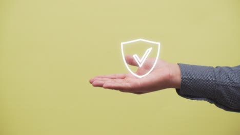 hand shows a shield with a check mark icon on yellow background