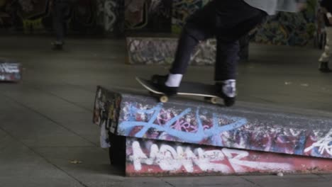 skateboarder fails to do a trick while people are skateboarding in the skate park southbank center, london, uk