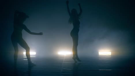 silhouette dancer women performing dance figures in fog