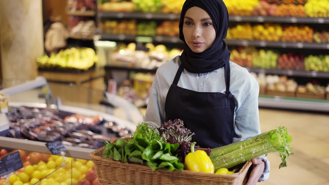 mujer musulmana en hijab camina con una canasta de verduras frescas en el supermercado, de cerca
